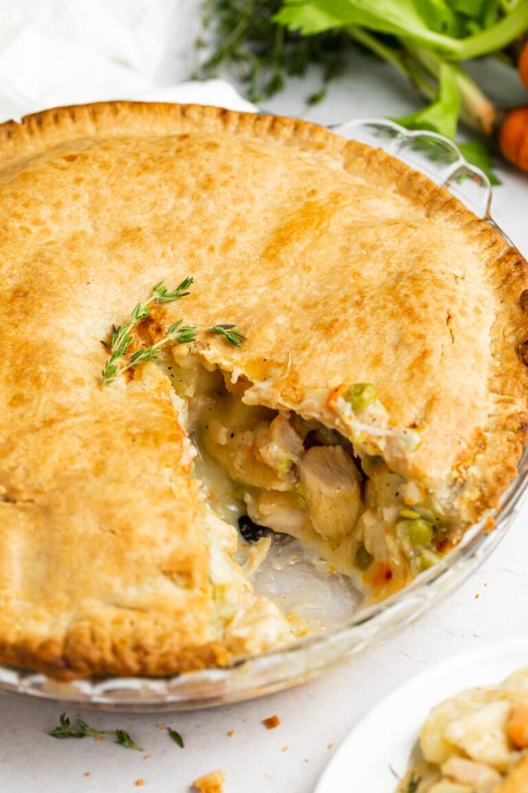 chicken pot pie with a slice removed and carrots on the side