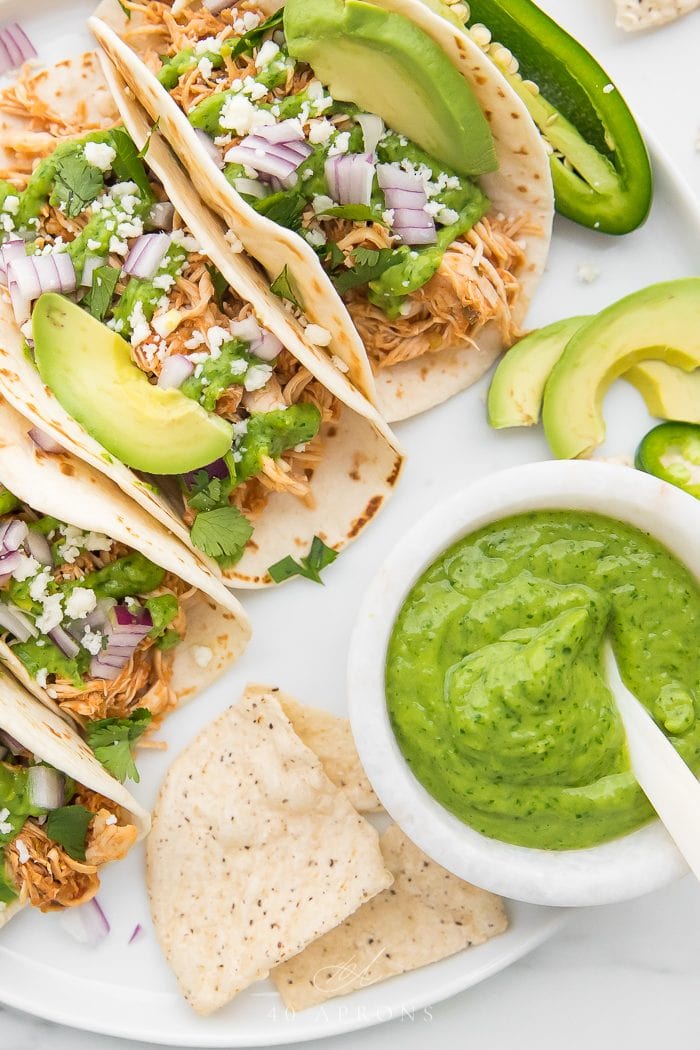 Crockpot chicken tacos with a bowl of avocado cilantro sauce