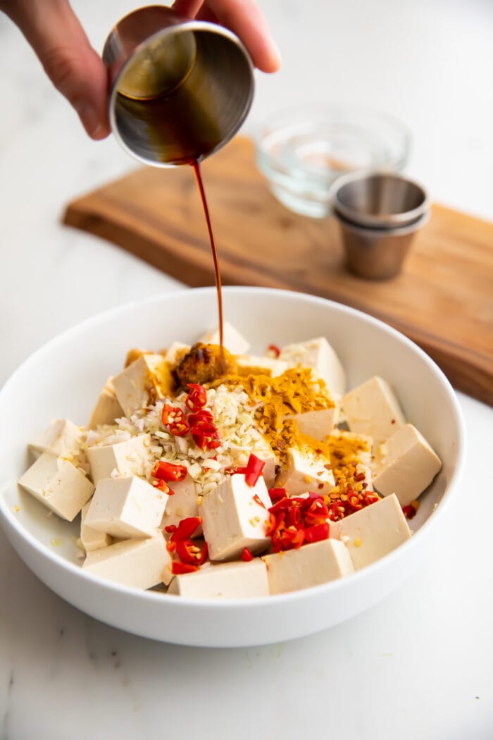 Lemongrass tofu marinade poured over tofu in a large bowl