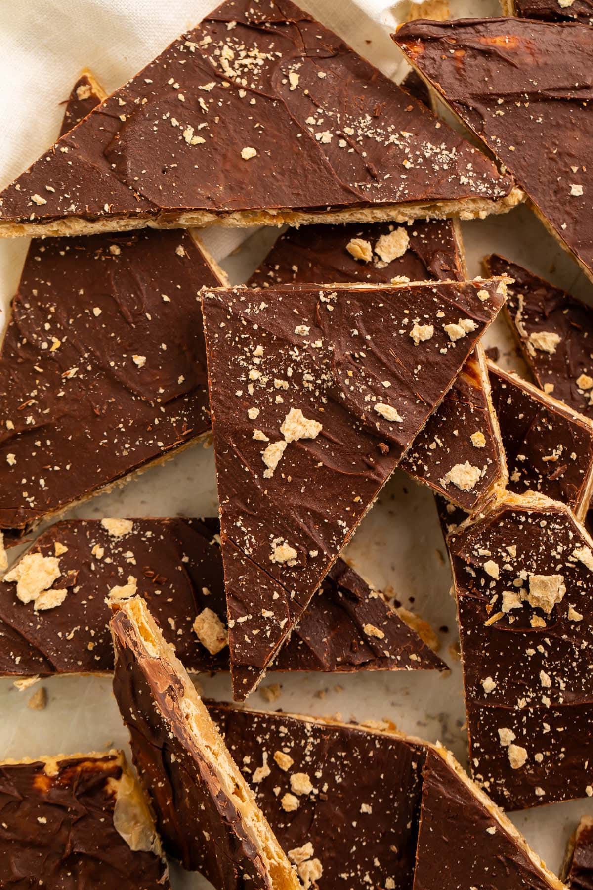 Broken pieces of saltine toffee in a pile on a piece of parchment paper.