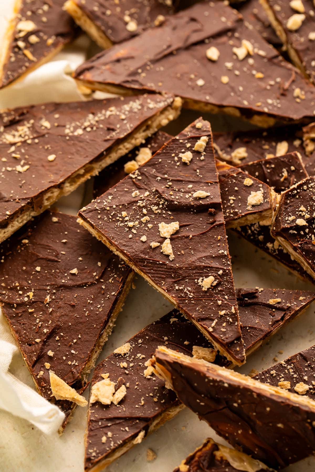 Broken pieces of saltine toffee in a pile on a piece of parchment paper.