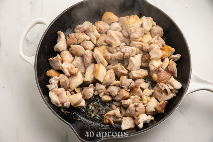 Salted chicken thighs cut into bite-sized pieces and piled into a wok to stir fry.