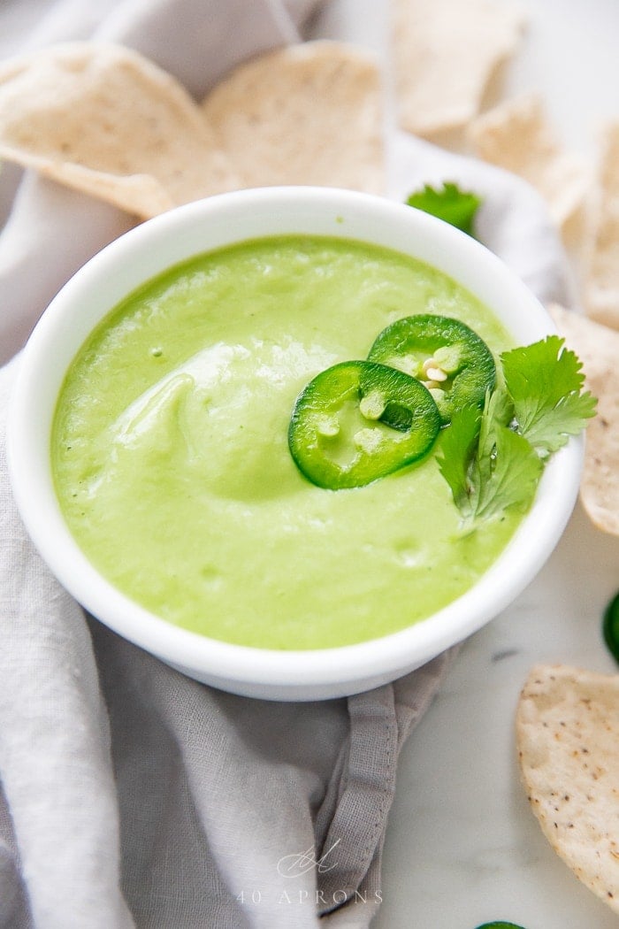 Avocado salsa in a white bowl at an angle, surrounded by chips