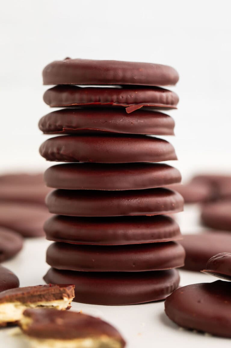 A tall stack of vegan thin mints on a table surrounded by other thin mint cookies.