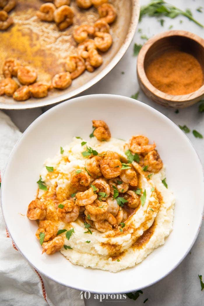 Whole30 healthy shrimp and grits in a bowl with skillet in background