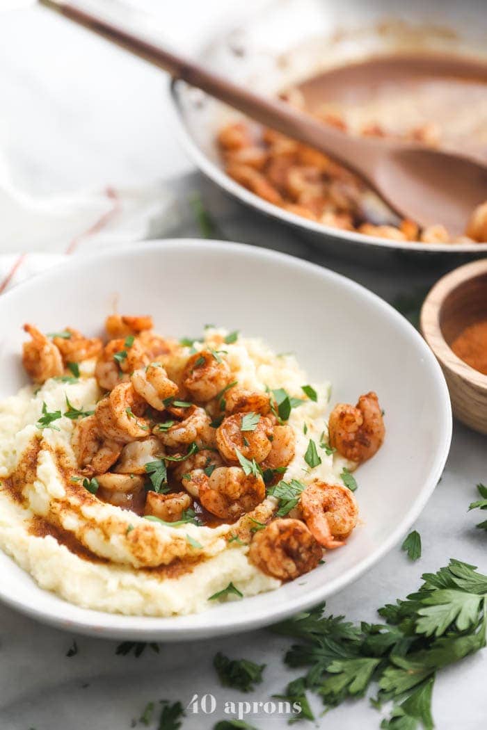 Whole30 healthy shrimp and grits in a bowl with skillet in background