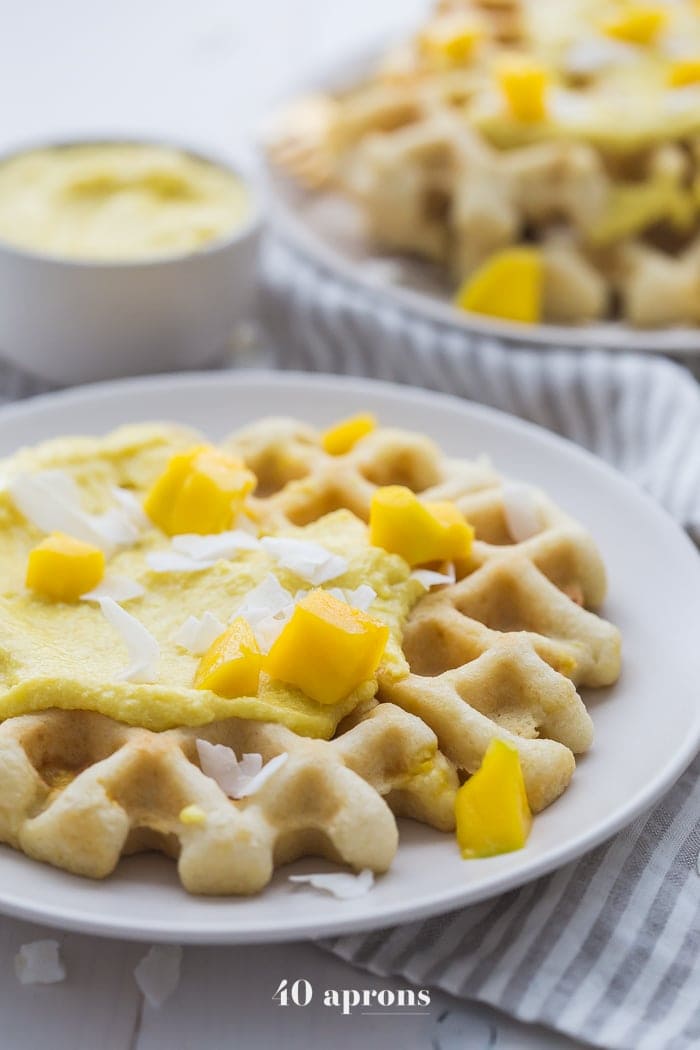 These are the best paleo waffles, topped with sweet mango cream. They're tender and light, sweet and flavorful. Topped with a sweet mango cream made from healthy, real ingredients, this dish will become your favorite paleo breakfast recipe! And if you're asking me, this is the best paleo waffle recipe - the texture is light and fluffy, but you'll feel energized instead of sluggish after a stack. Perfect for spring and summer!