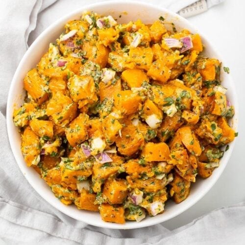 Sweet potato salad in a white bowl on a marble countertop