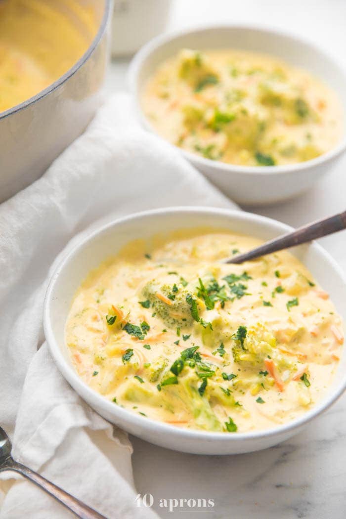 Cheesy vegan broccoli soup in two bowls with soup pot in background