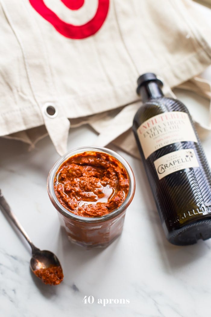 overhead shot of a small side dish of homemade harissa spice paste next to a bottle of olive oil 