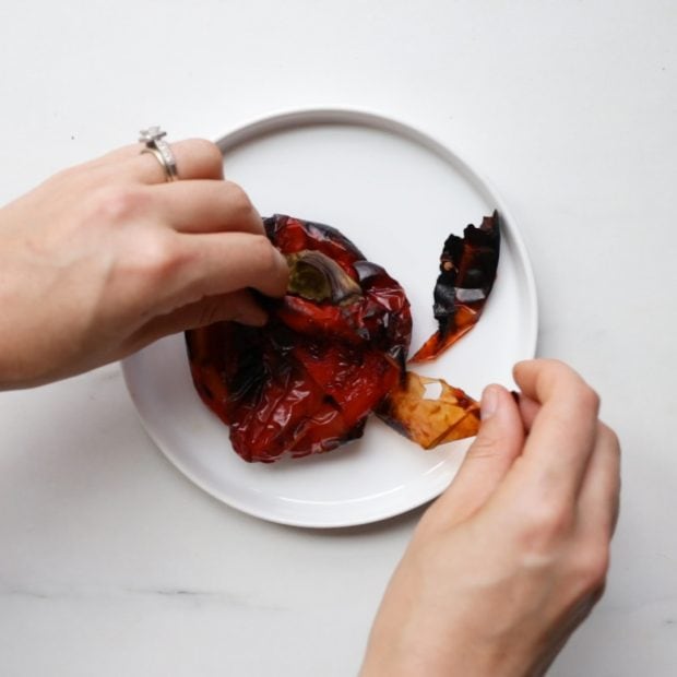 a roasted red bell pepper being peeled