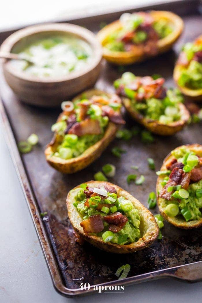 These paleo potato skins are seriously perfect paleo tailgate food. These paleo potato skins are super crispy and easy to make, loaded with a quick guacamole, crispy bacon, green onions, and ranch dressing. Yep, these Whole30 potato skins are perfect alongside buffalo wings and beer, and they'll quickly become your favorite paleo tailgate food. 