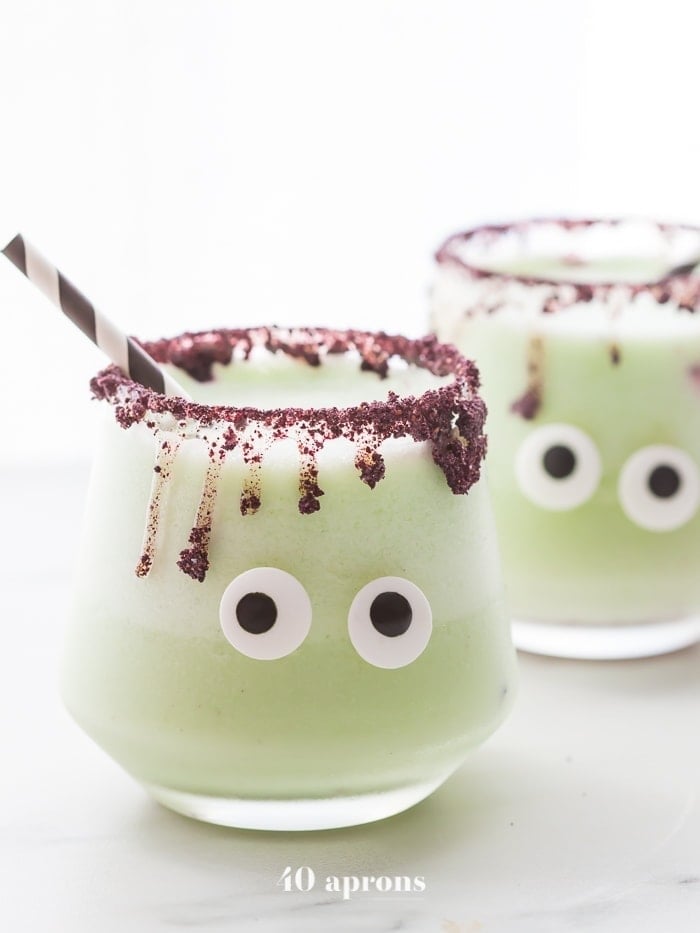 These "monsteritas" are healthy Halloween margaritas spiked with cucumber and jalapeño for a trick and treat all in one! Sweetened with honey, these healthy Halloween margaritas are super festive and fun without any refined sugar or artificial coloring. With a freeze-dried blueberry rim and two candy eyes, these healthy Halloween margaritas are a must make for any adult Halloween party!