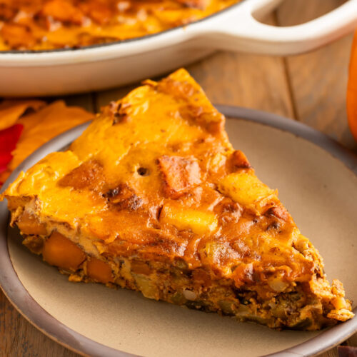 A triangular slice of a paleo pumpkin breakfast bake served on a small tan plate.