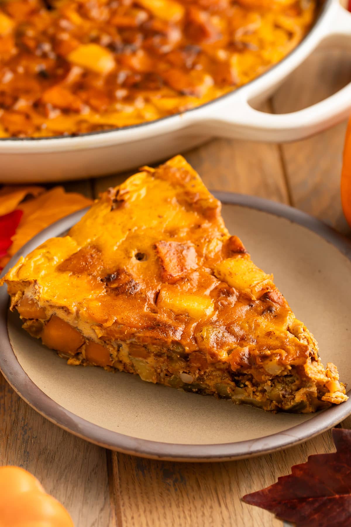 A triangular slice of a paleo pumpkin breakfast bake served on a small tan plate.