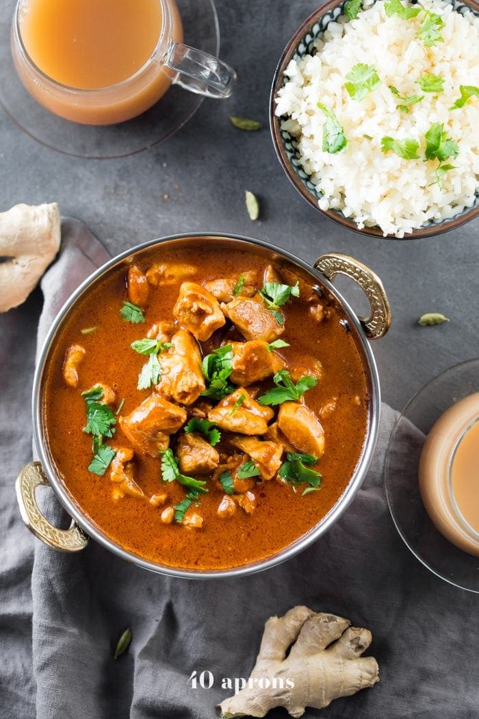 Whole30 Indian butter chicken in a bowl with cauliflower rice and chai tea