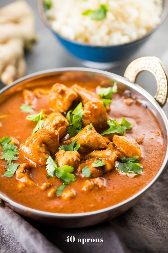 Whole30 Indian butter chicken in a bowl with cauliflower rice and chai tea