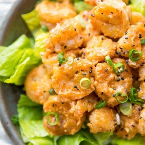 Whole30 bang bang shrimp topped with green onions and sesame seeds on a bed of romaine lettuce