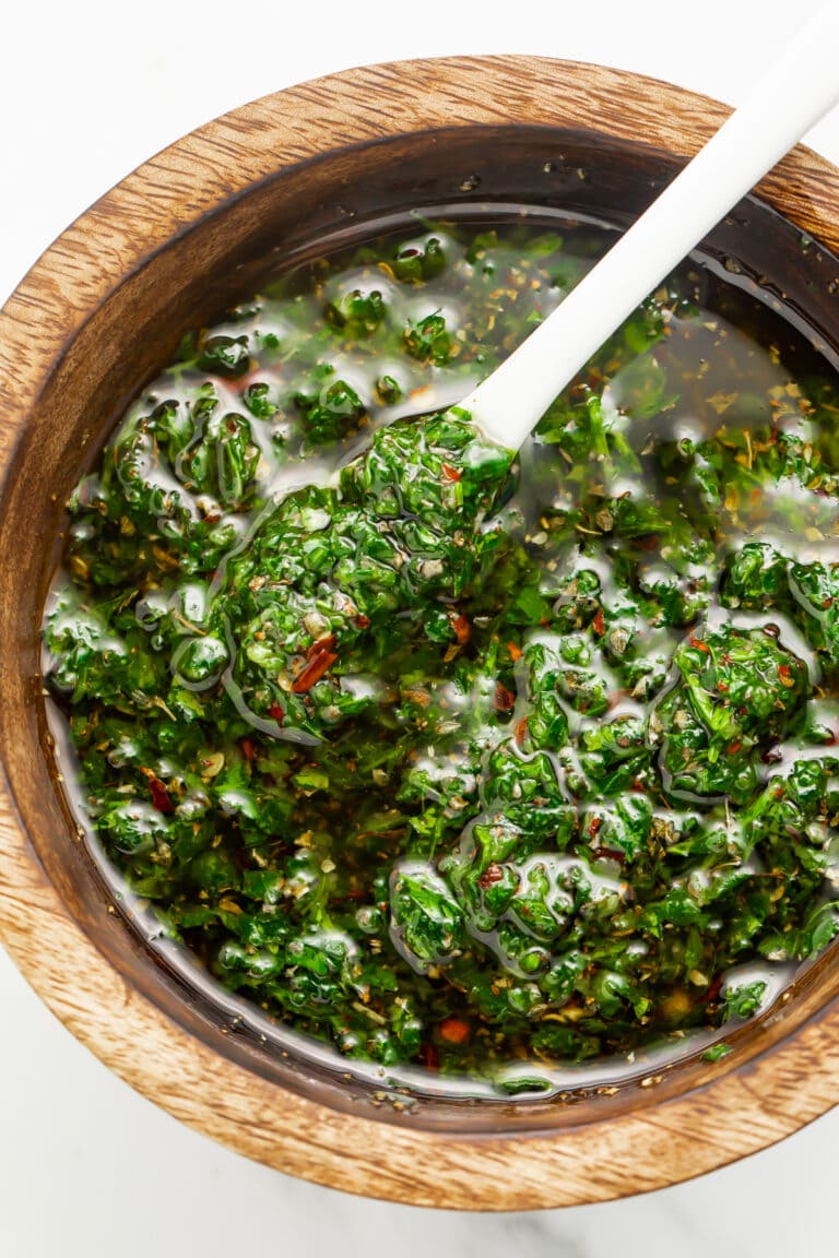 Overhead view of Texas de Brazil chimichurri sauce in a small wooden bowl with a spoon.