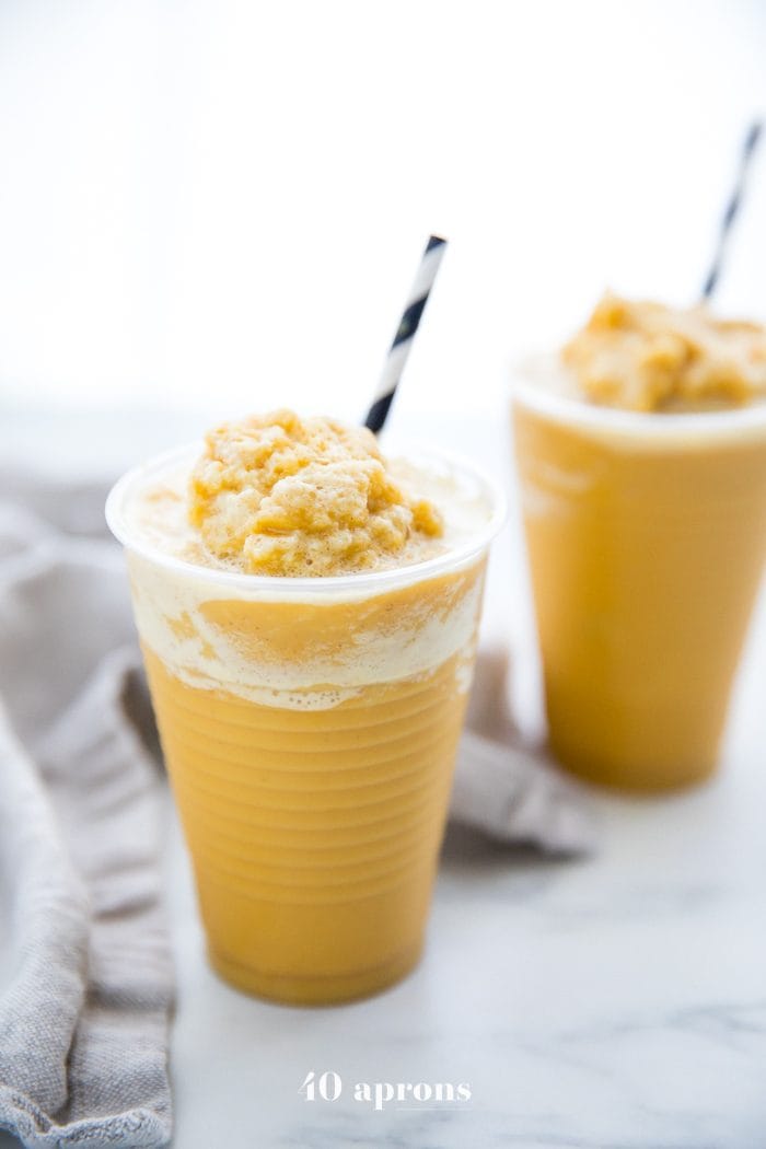 Two frozen golden milk turmeric frappuccinos in to-go cups with black and white straws