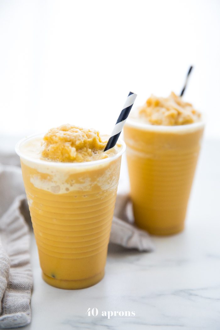 Two frozen golden milk turmeric frappuccinos in to-go cups with black and white straws