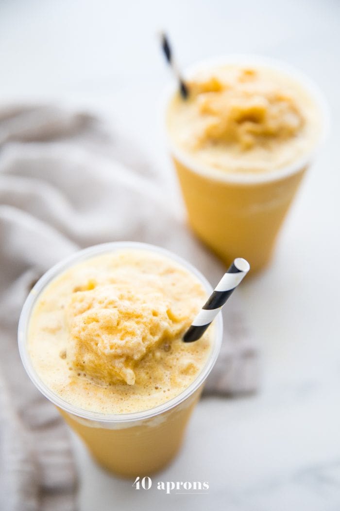 Two frozen golden milk turmeric frappuccinos in to-go cups with black and white straws