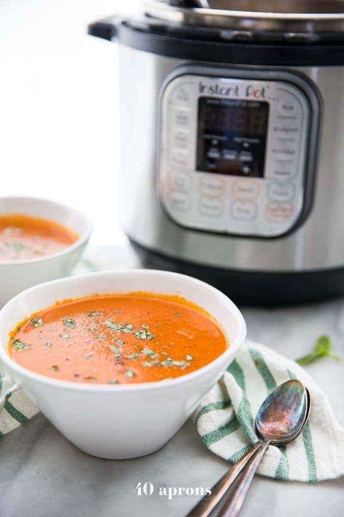 Perfect Whole30 Instant Pot tomato soup (vegan) in two bowls in front of the Instant Pot