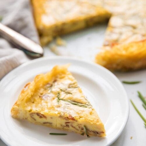 Whole30 quiche lorraine with hash brown crust slice with whole quiche in background