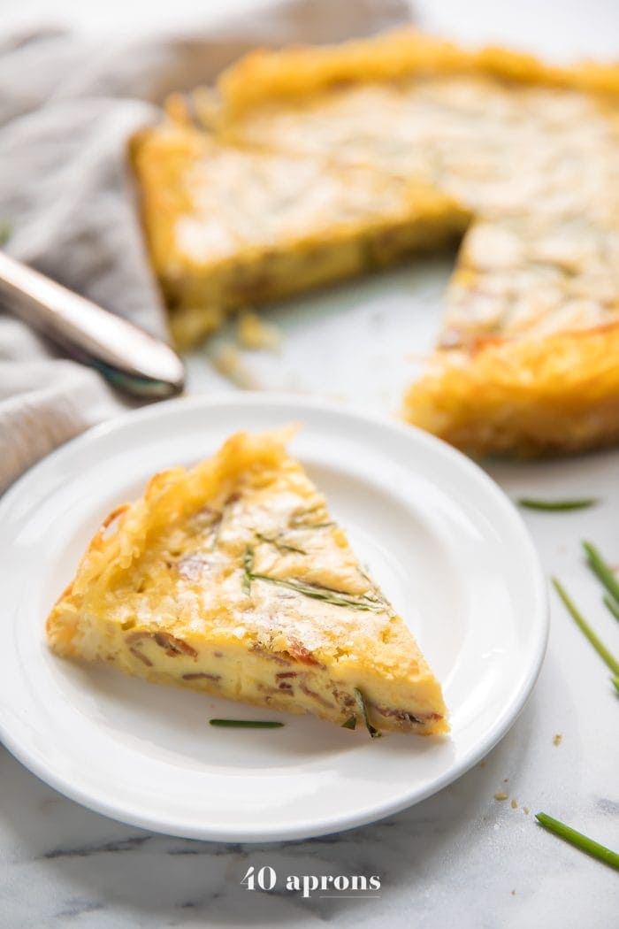 Whole30 quiche lorraine with hash brown crust slice with whole quiche in background