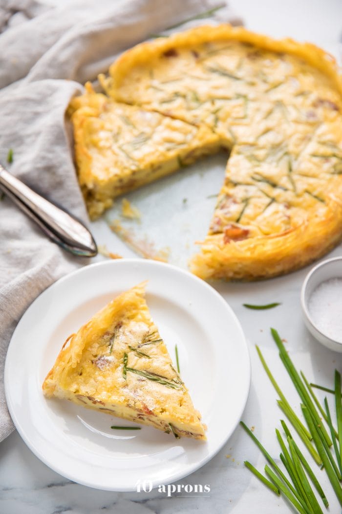 Whole30 quiche lorraine with hash brown crust slice with whole quiche in background