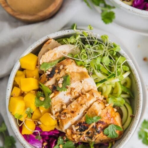 Whole30 Thai chicken zoodle bowls with "peanut sauce" in a bowl with garnishes