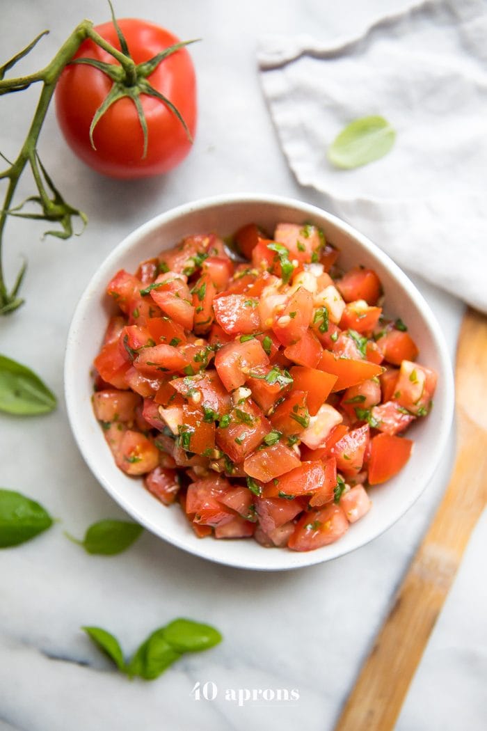 Bowl of fresh bruschetta with tomatoes, basil, and garlic, Tomatoes and fresh basil off to the side