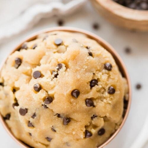 Healthy cookie dough in a copper bowl with a bowl of chocolate chips in the corner