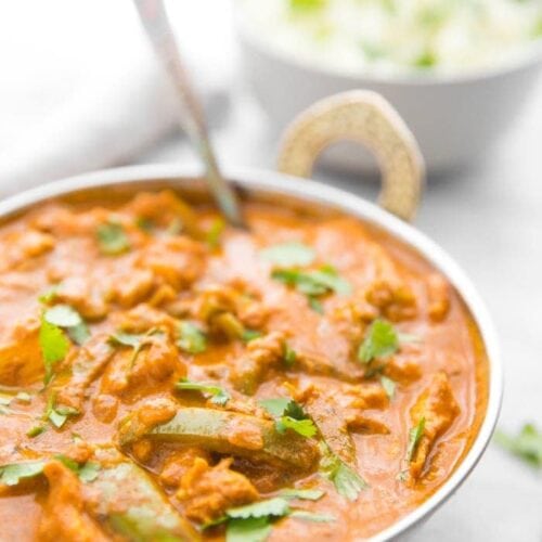 Instant Pot chicken tikka masala in a copper serving bowl with chopped cilantro and cauliflower rice in the background