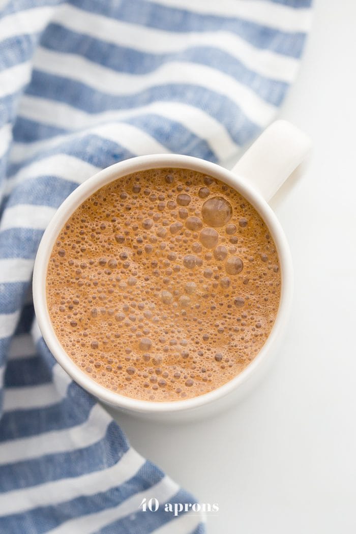 A mug of miracle maca latte with a blue-striped towel