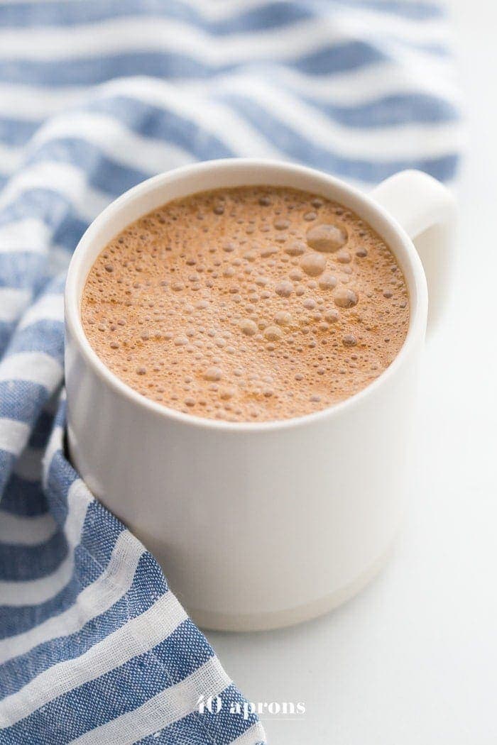 A mug of miracle maca latte with a blue-striped towel