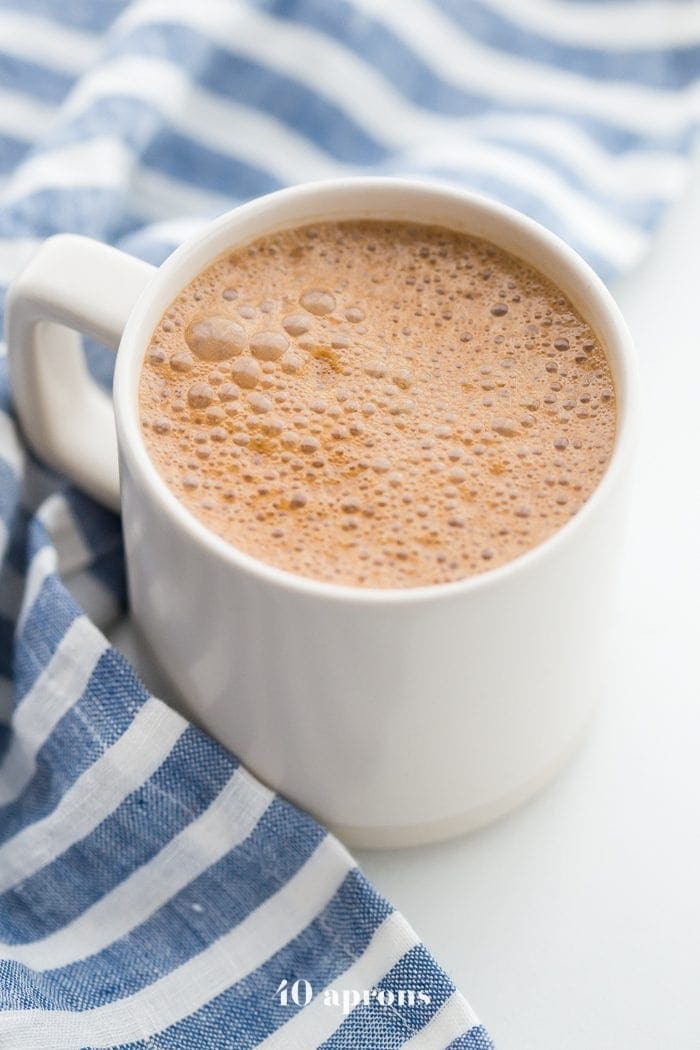 A mug of miracle maca latte with a blue-striped towel