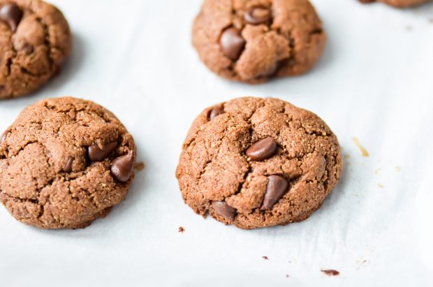 3 stacked Paleo freshly baked Double Chocolate Fudge Cookies on a parchment paper-lined tray.