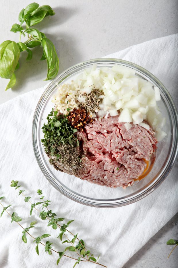 ingredients for Whole30 Meatballs in a glass bowl ready to be mixed.