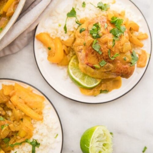 Coconut curry turmeric chicken on a plate with cilantro garnish and a lime to the side