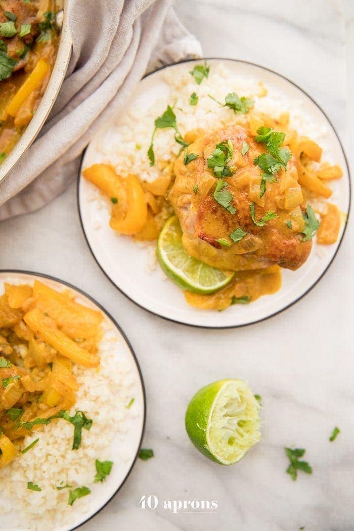 Coconut curry turmeric chicken on a plate with cilantro garnish and a lime to the side