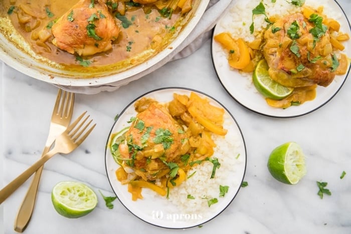 Coconut curry turmeric chicken on a plate with cilantro garnish and a lime to the side