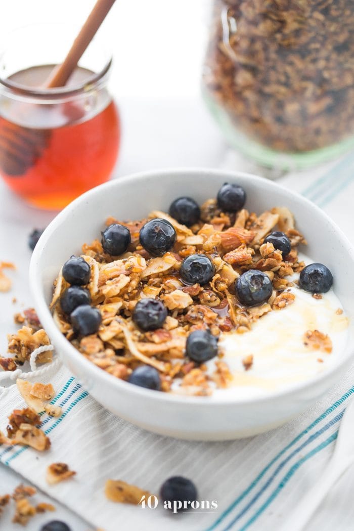 Bowl of the crunchy paleo granola recipe over yogurt, topped with blueberries 