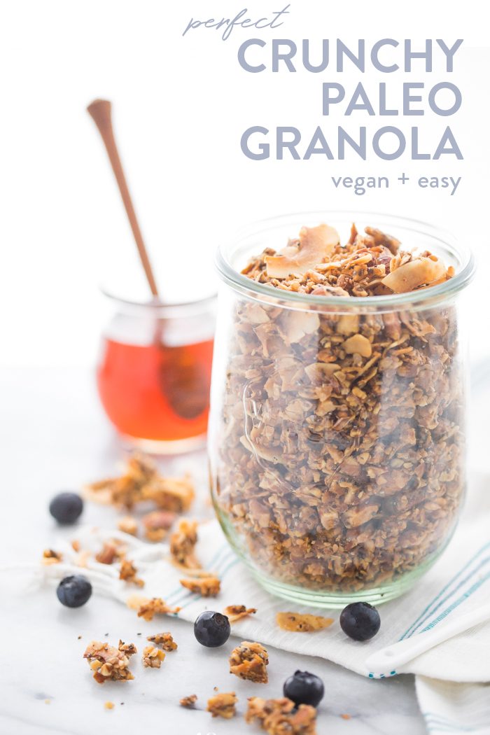 A glass jar of a crunchy paleo granola recipe with a jar of honey in the background