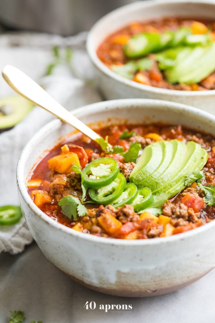 Two bowls of Instant Pot Whole30 chili with butternut squash topped with jalapenos and avocados