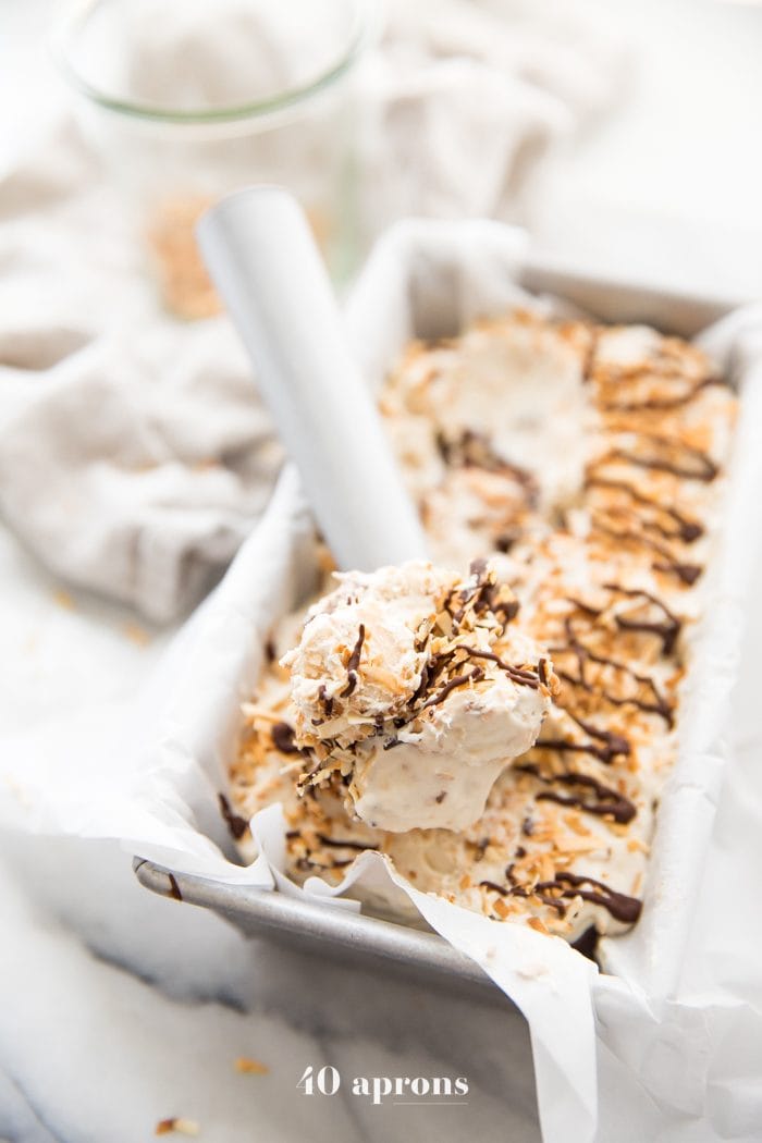 Scoop of Samoas cookies ice cream in an ice cream scoop on top of container of ice cream