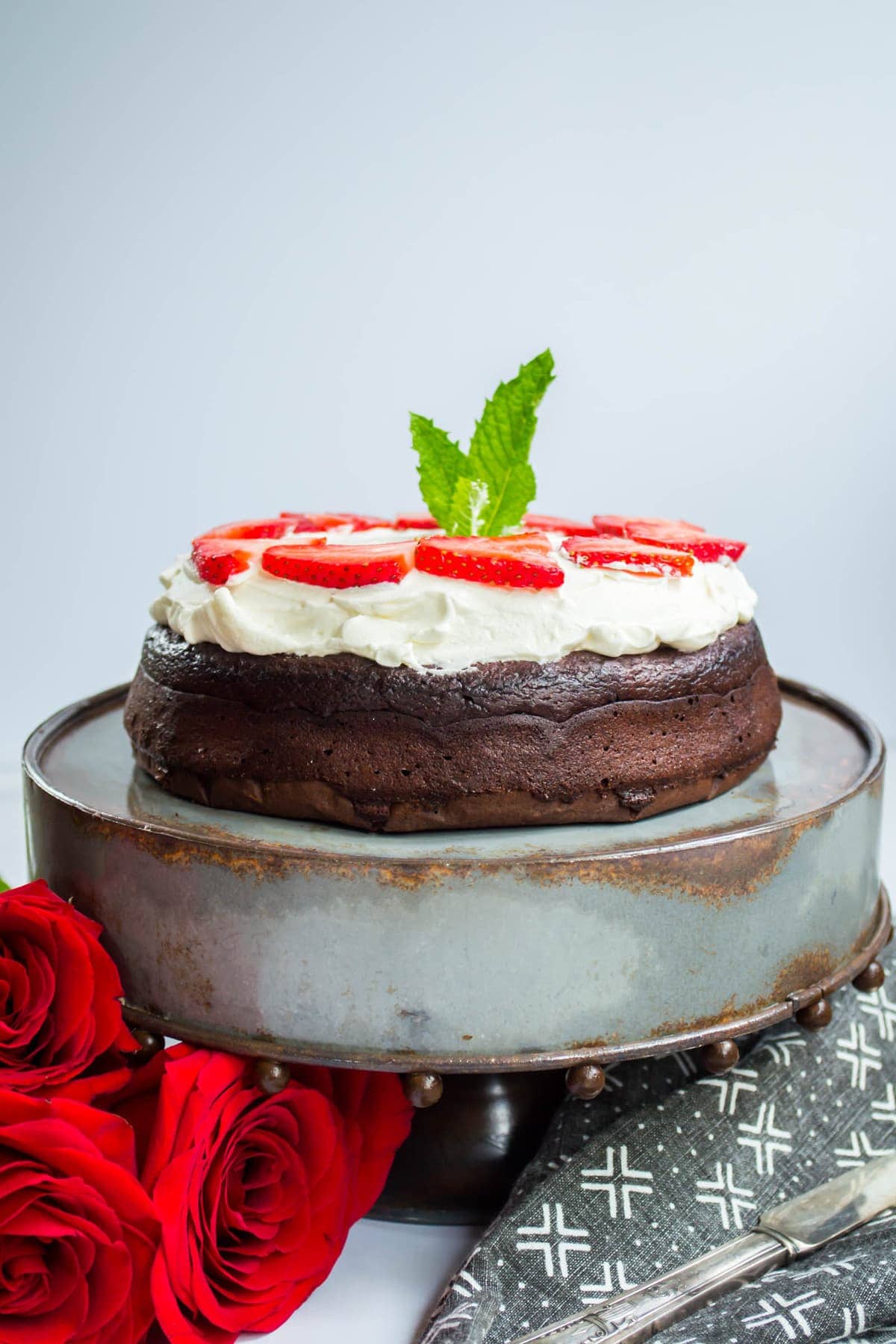 Keto Flourless Chocolate Dessert Torte topped with whipped cream on a cake stand