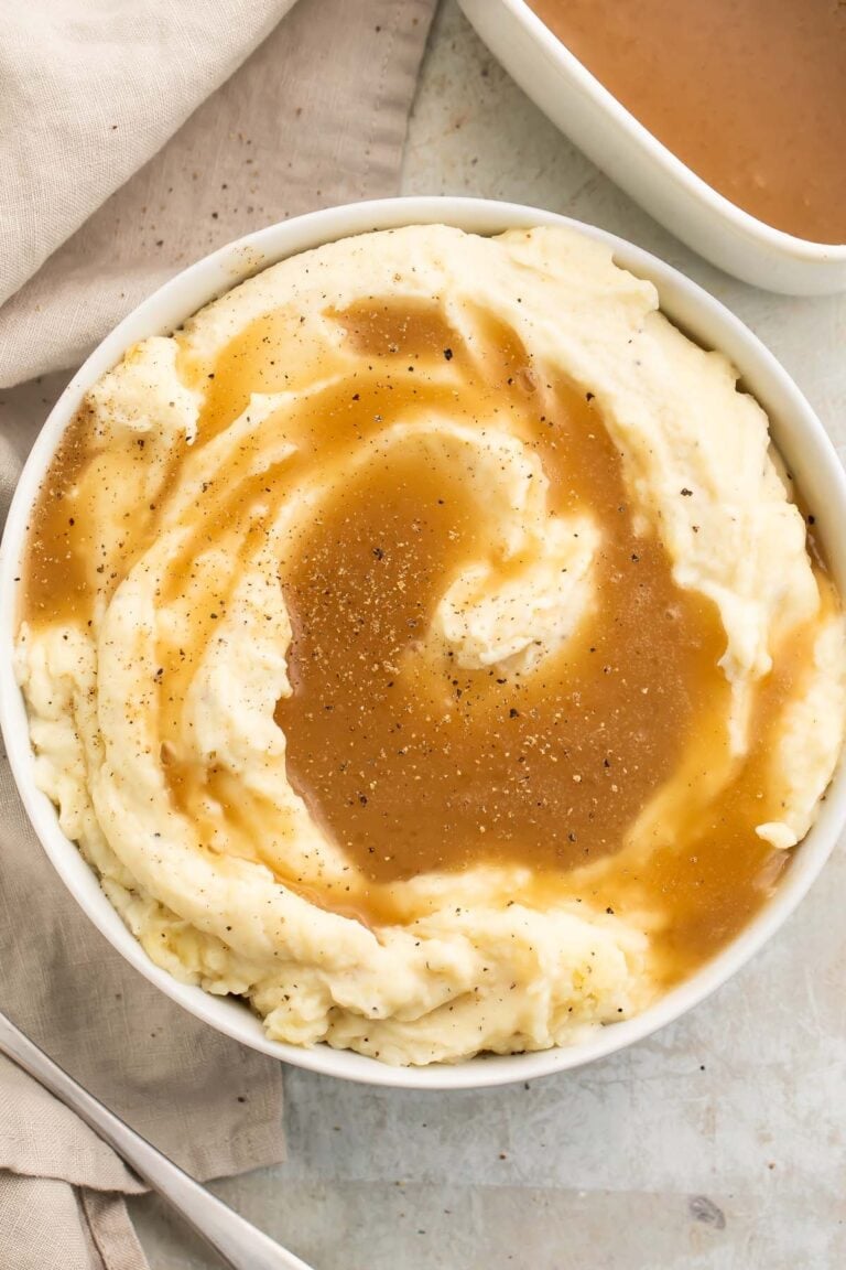 Top-down view of a large bowl of mashed potatoes topped with rich brown paleo gravy.