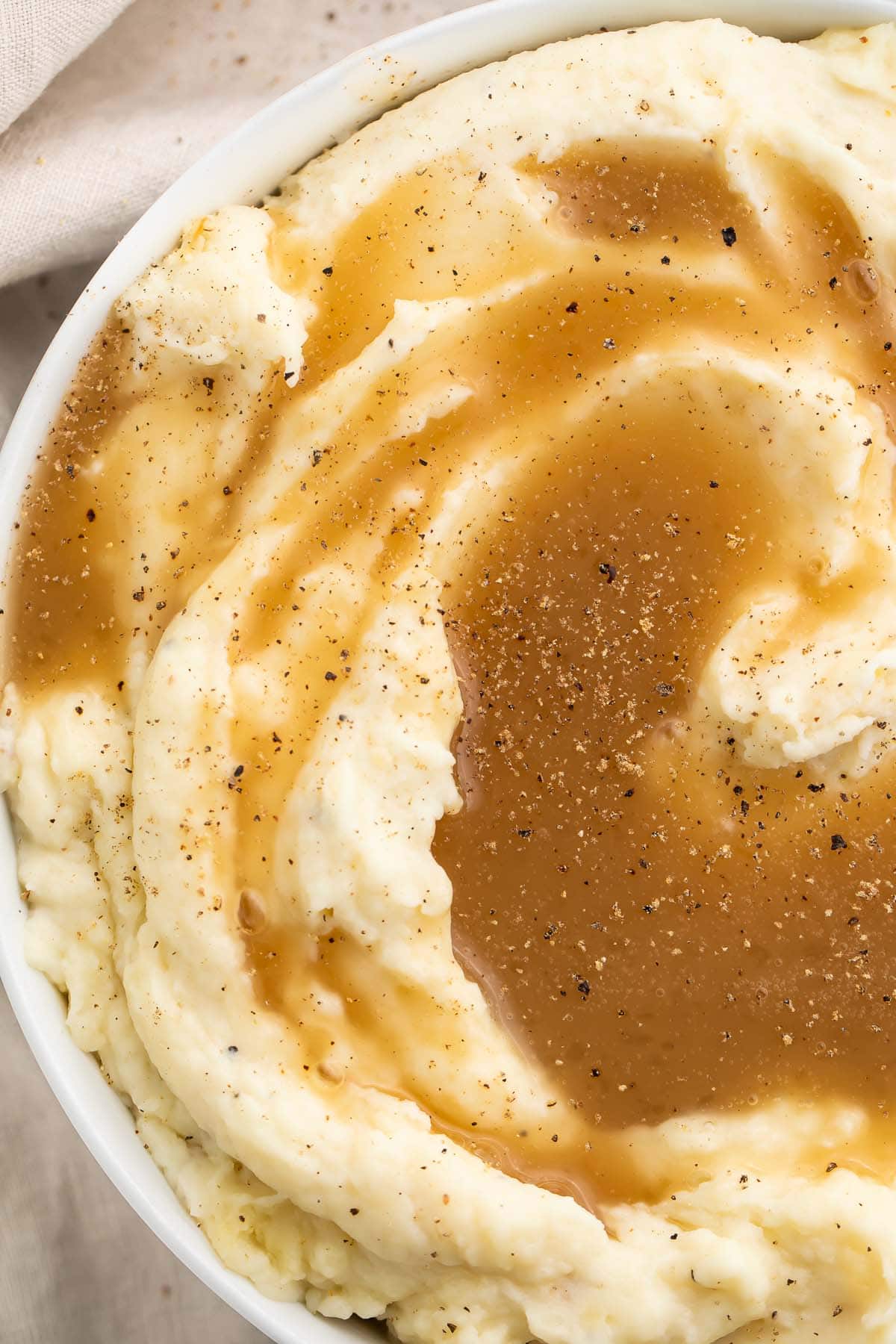 Top-down view of a large bowl of mashed potatoes topped with rich brown paleo gravy.