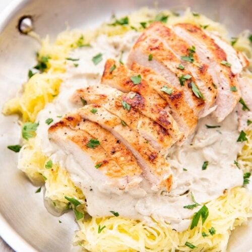 Healthy Whole30 chicken alfredo with spaghetti squash in a skillet topped with parsley